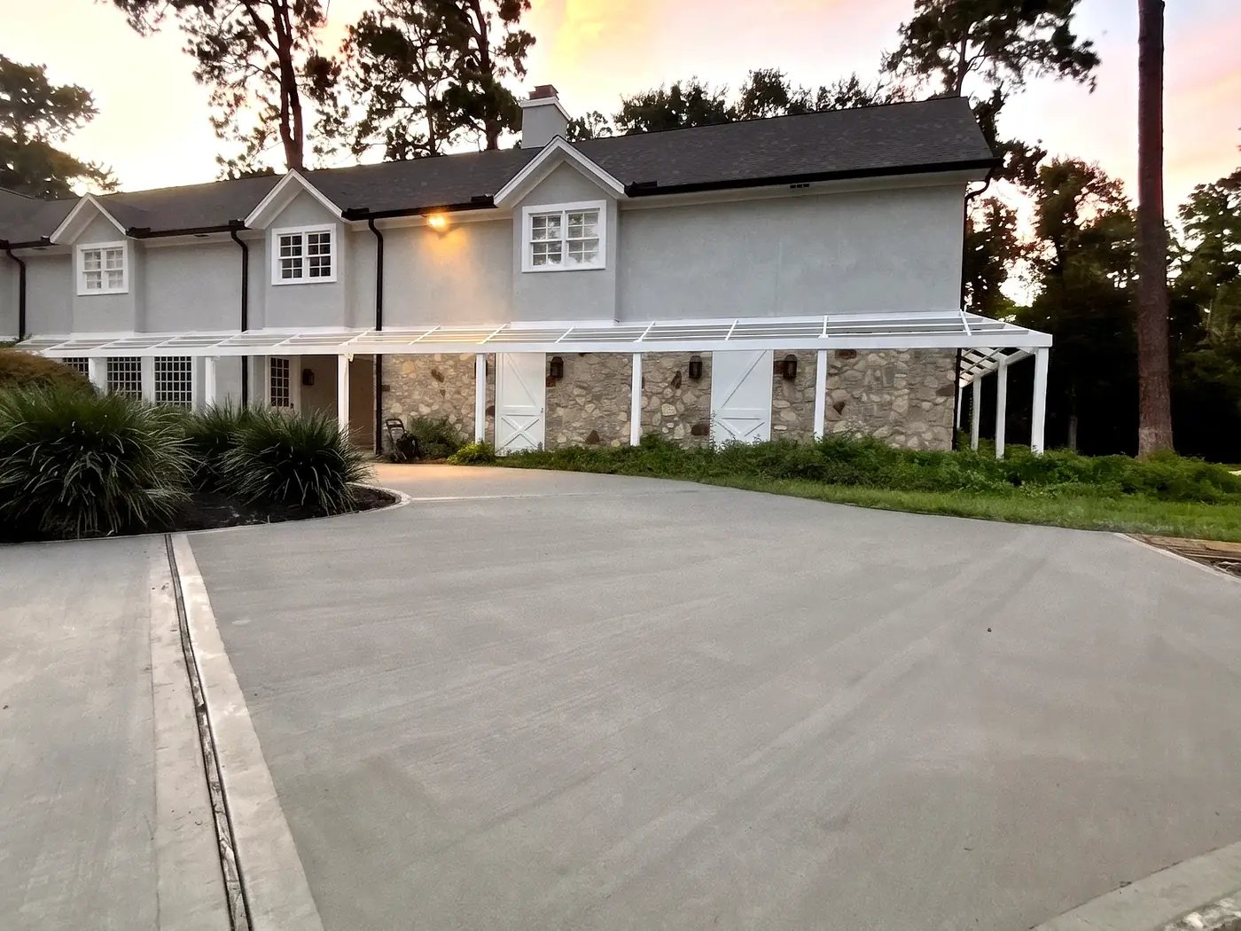 Finished concrete driveway with border bands in front of a stone-accented home at twilight