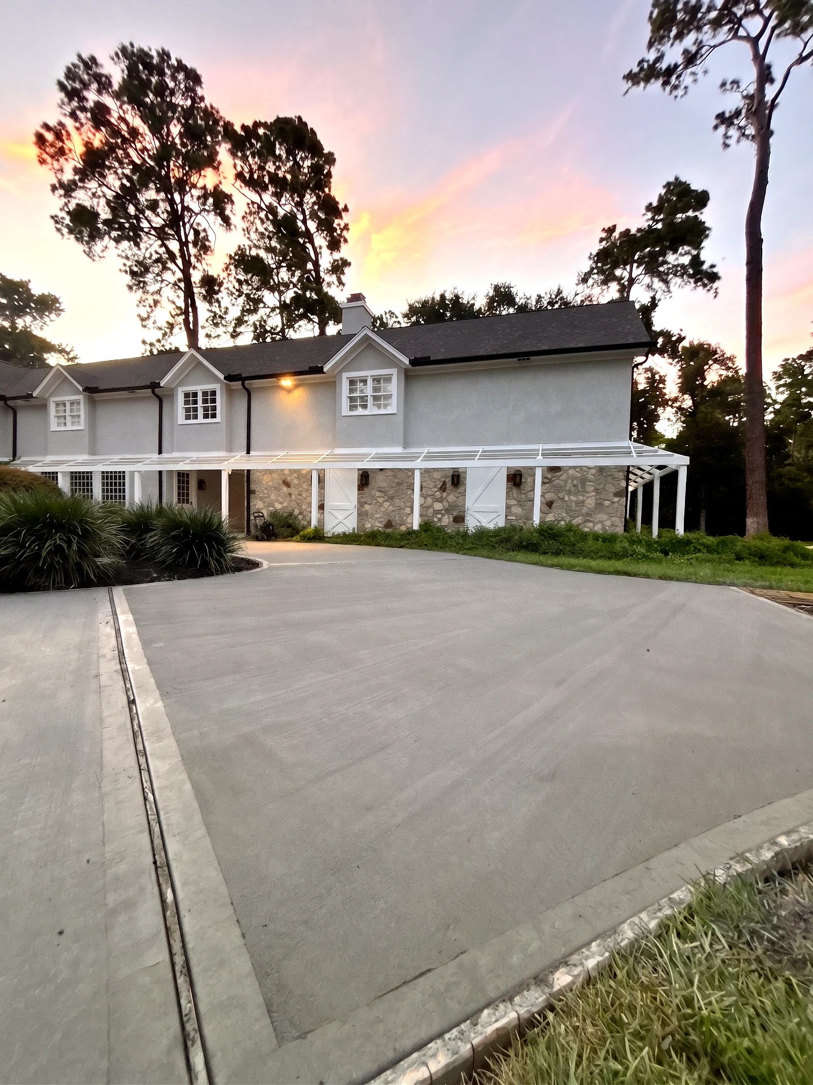Finished concrete driveway with border bands in front of a stone-accented home at twilight