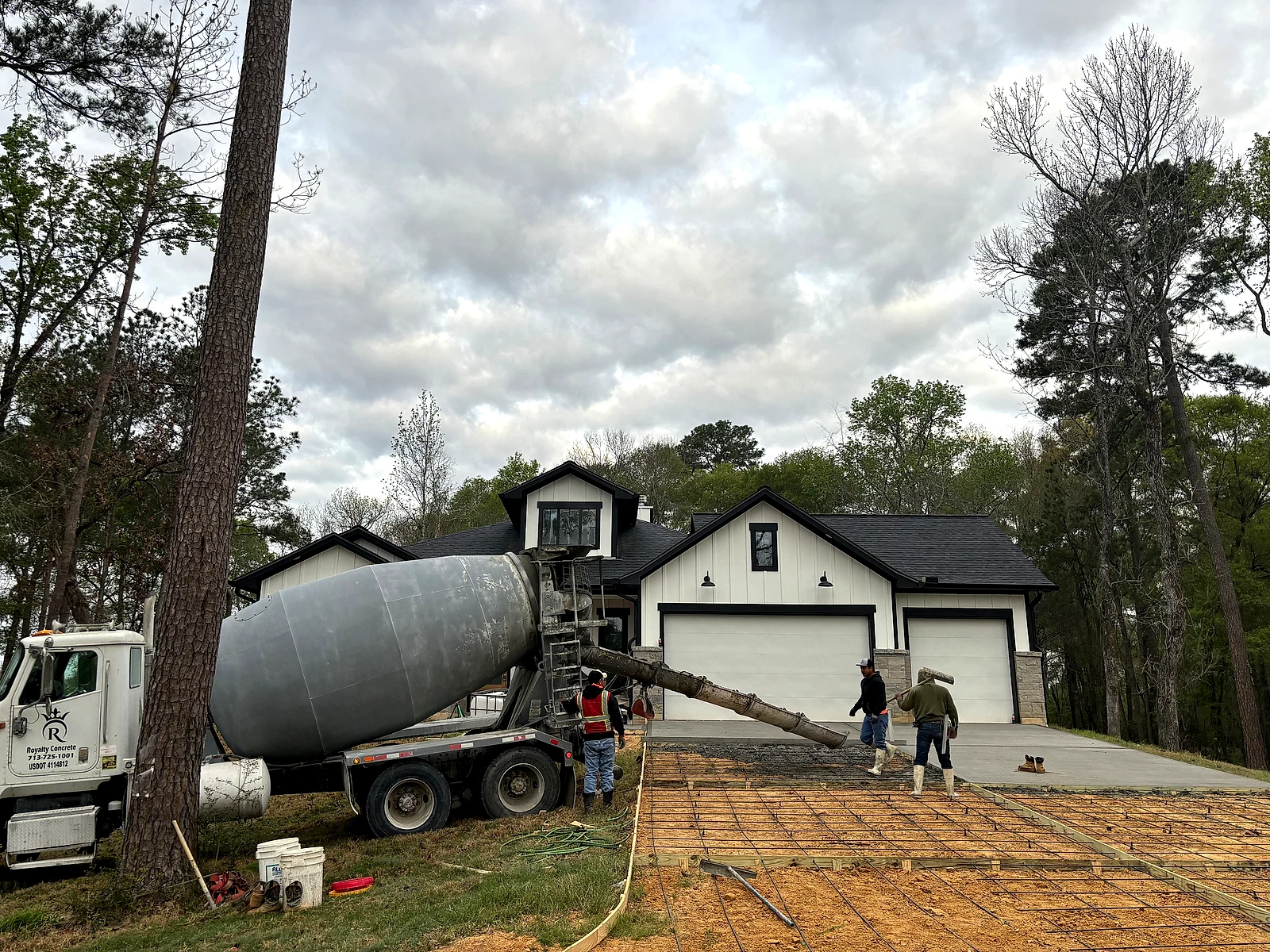 Ready-mix truck and crew placing concrete on a residential foundation pour day