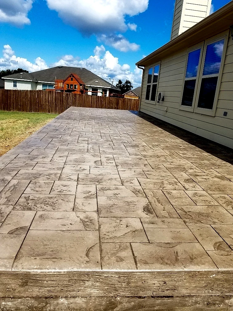 Stamped concrete patio in an ashlar slate pattern behind a home under a blue sky